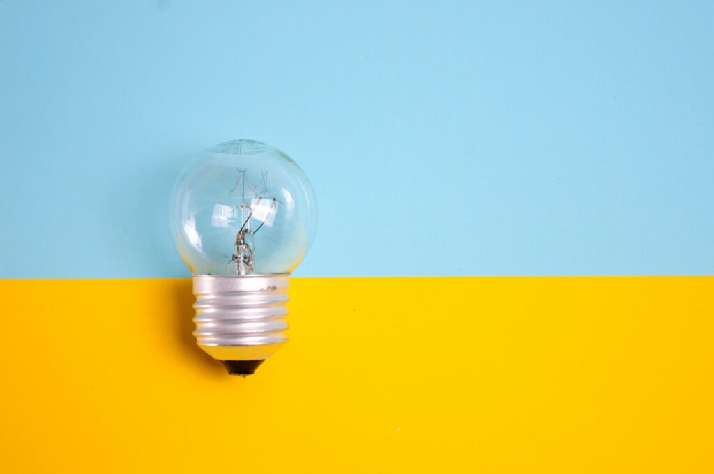 Hetlichtgezien A clear light bulb against a vibrant blue and yellow background, symbolizing energy and creativity.